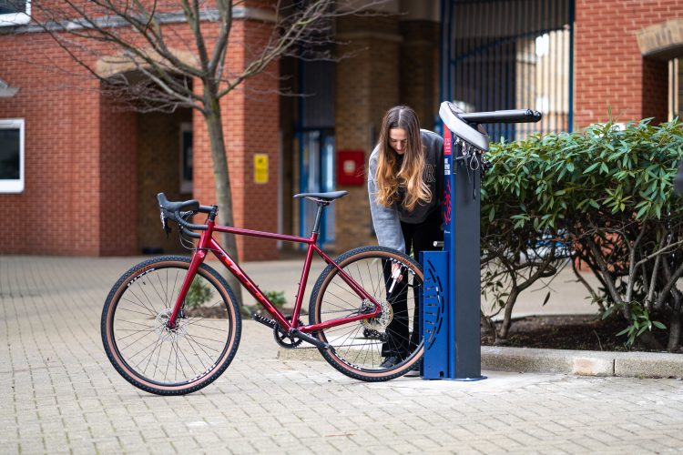 Cyclist using the Cyclehoop Deluxe Bike Repair Station to repair a bike