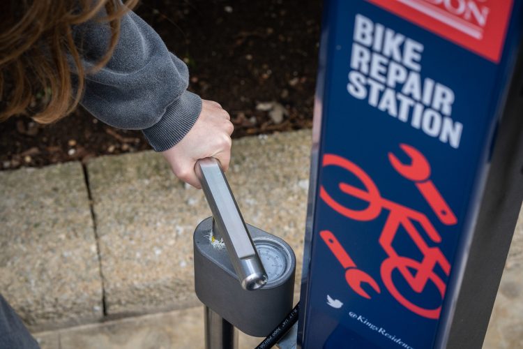 Cyclist using pump in the Deluxe Repair Station to fix a deflated tyre