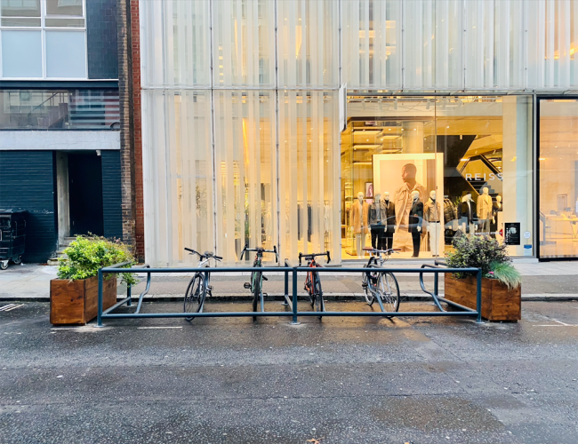 Cyclehoop Mobility Corral on a street with planters on either side and 4 bikes parked in between